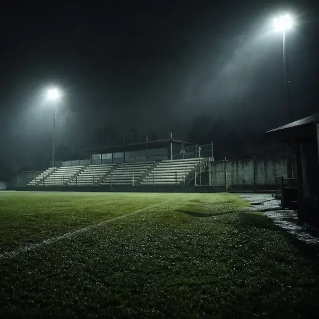Cancha de fútbol de noche bajo las torres de luz.